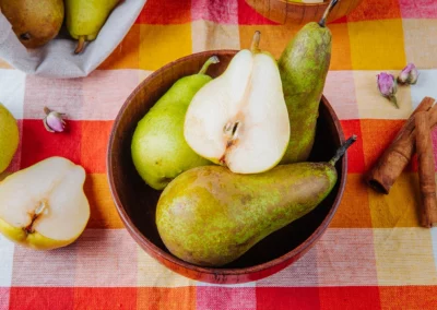 Whole and halved pears in a wooden bowl with cinnamon